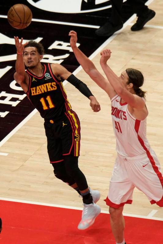 Atlanta Hawks guard Trae Young (11) shoots as Houston Rockets forward Kelly Olynyk (41) rushes ...