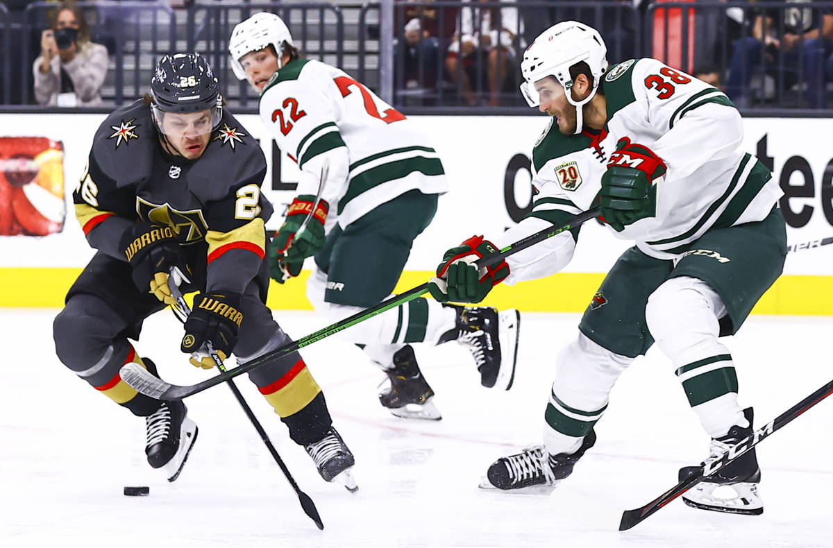 Golden Knights' Mattias Janmark (26) skates with the puck under pressure from Minnesota Wild's ...