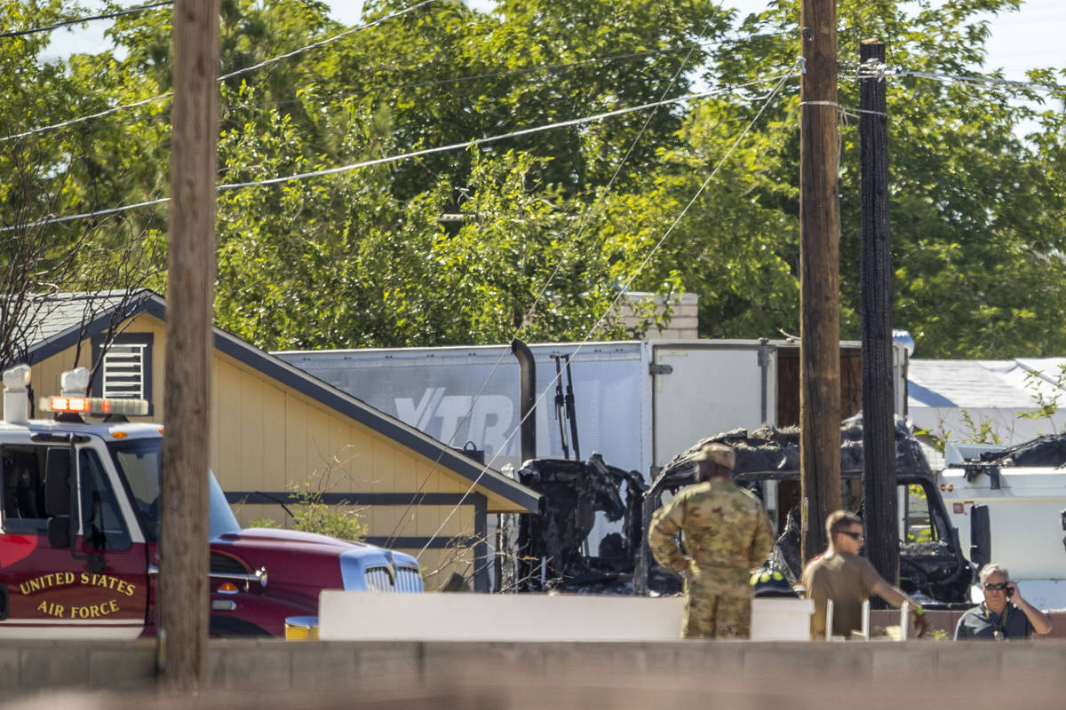 Military personnel look to a burned out vehicle near where a Nellis Air Force Base jet crashed ...