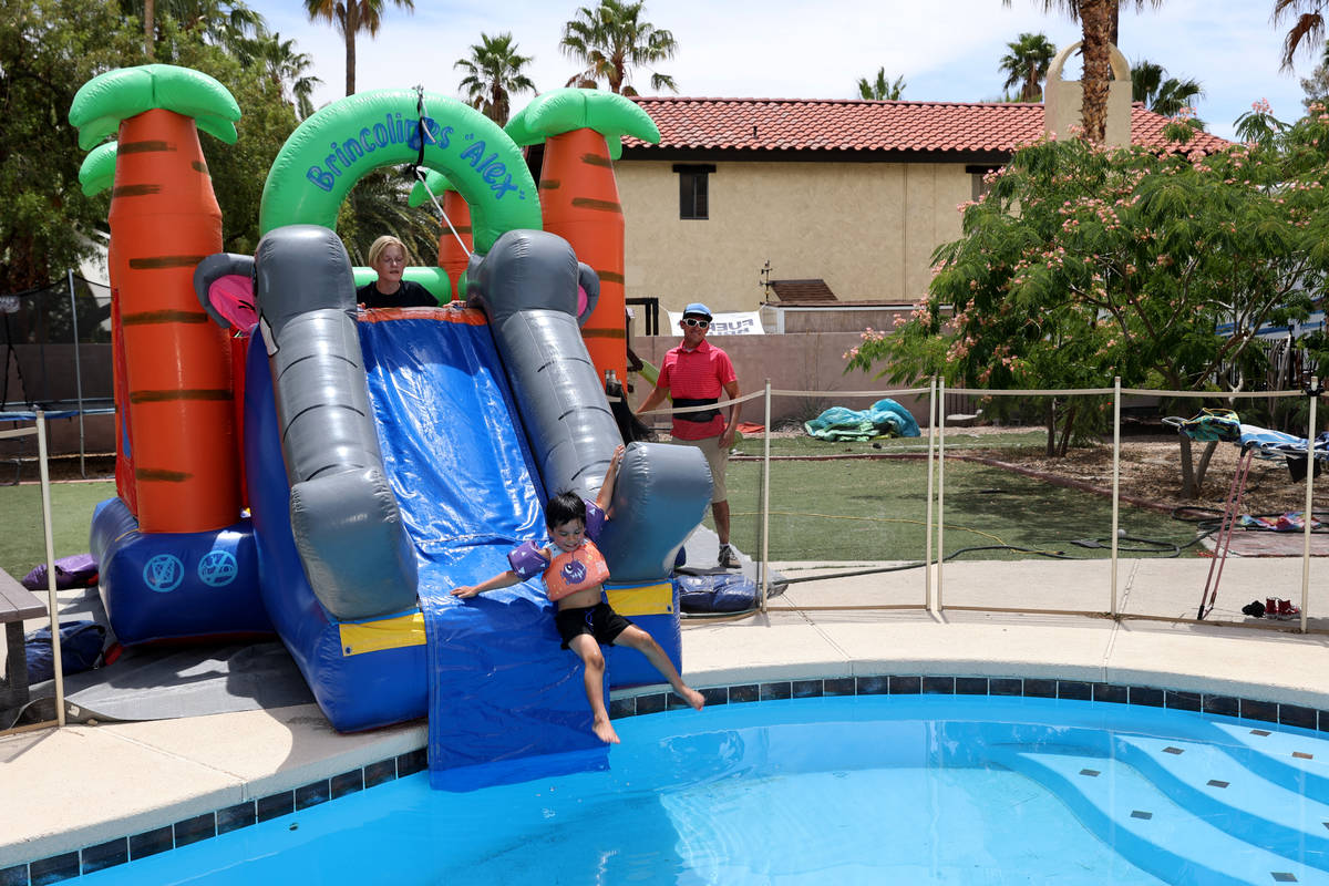 Benjamin David Hairr, 4, slides into the pool with the help of his brother James Heath Hairr, 1 ...
