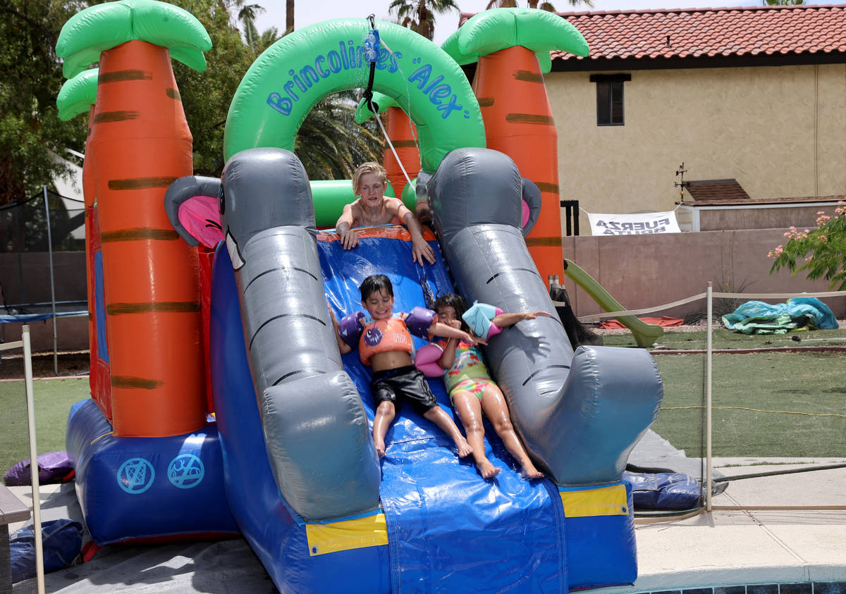 Benjamin David Hairr, 4, and Genesis Marie Hairr, 6, slide into the pool with the help of their ...