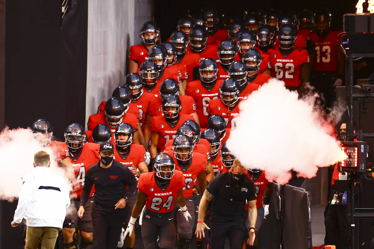 UNLV Rebels players run onto the field before taking on the Wyoming Cowboys in a football game ...