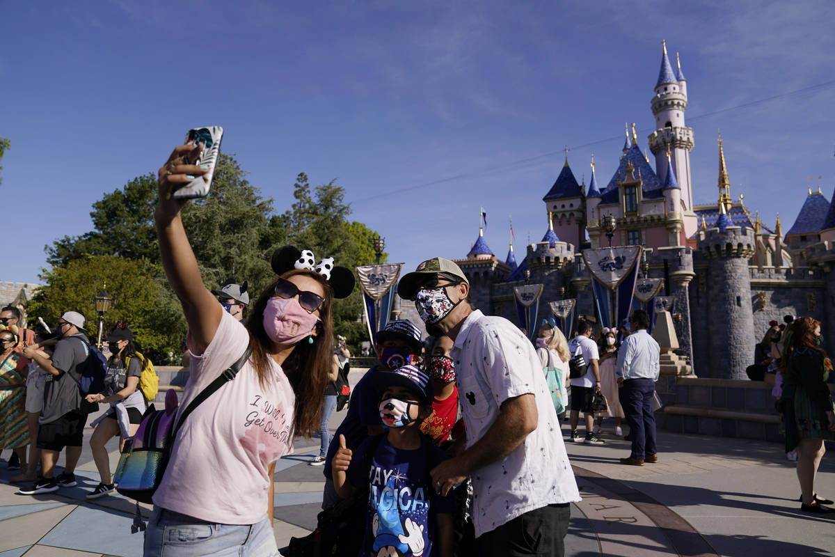 A family takes a photo in front of Sleeping Beauty's Castle at Disneyland in Anaheim, Calif., F ...