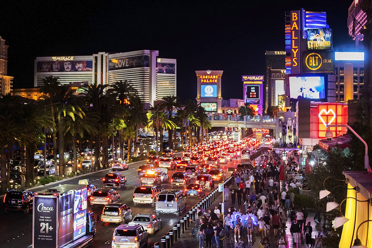 FILE - In this March 19, 2021, file photo, vehicles and crowds move along the strip in Las Vega ...