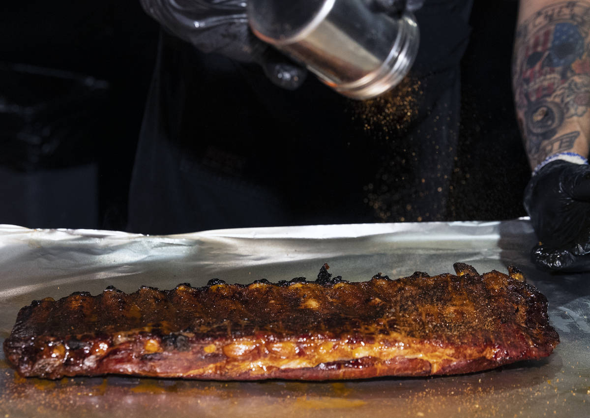Joe Woodel, BBQ pitmaster, sprinkles seasoning on a rack of pork ribs at The Beast by Todd Eng ...