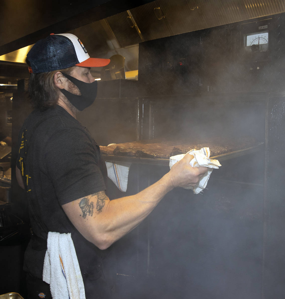 Joe Woodel, BBQ pitmaster, takes racks of smoked pork ribs out of the smoker at The Beast by To ...