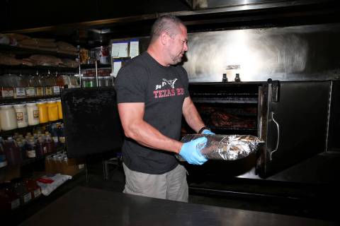 Brian Buechner, owner of Big B's Texas BBQ in Henderson, places a wrapped brisket in a BBQ pit ...