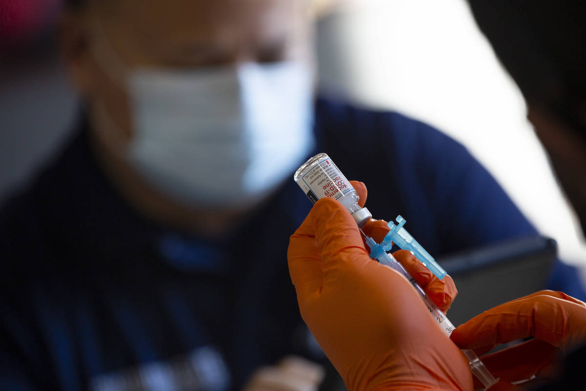 Paramedic Craig Johnson draws a dose of the Moderna COVID-19 vaccine in preparation for Guardia ...