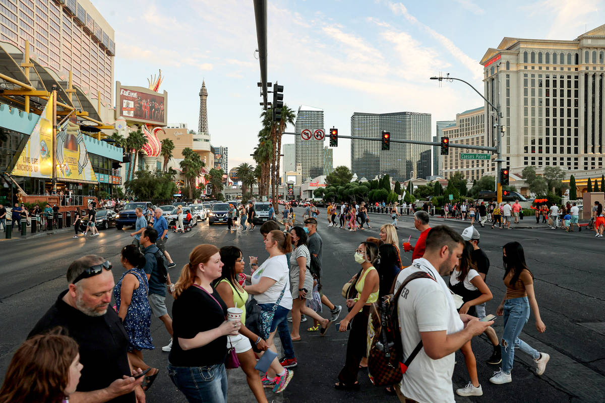 Crowds cross the Strip at between the Linq Promenade and Caesars Palace in Las Vegas Friday, Ma ...