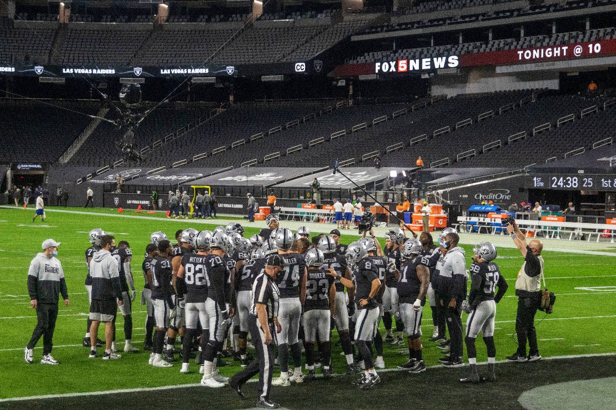 The Raiders huddle before an NFL football game against the Miami Dolphins with no fans in atten ...