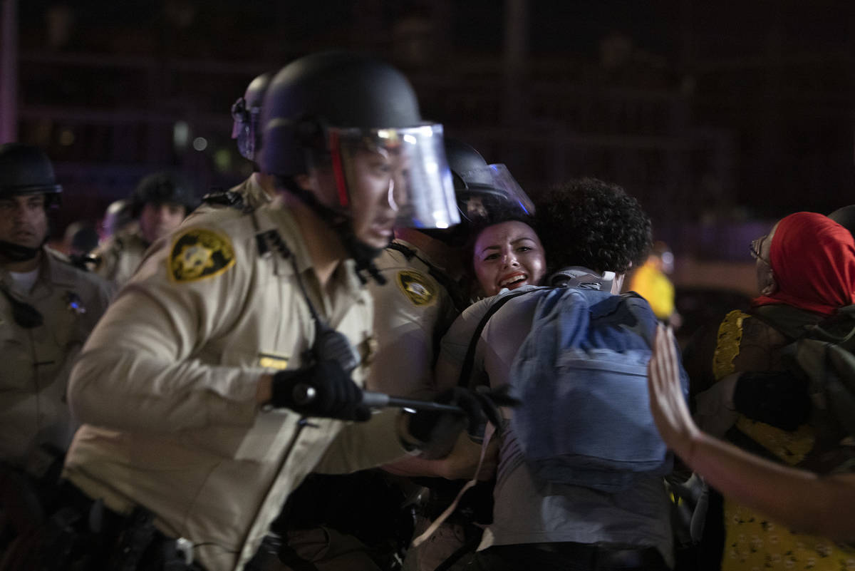 Annelise Friedman is swept away as Las Vegas police descend on a gas station parking lot at Fla ...