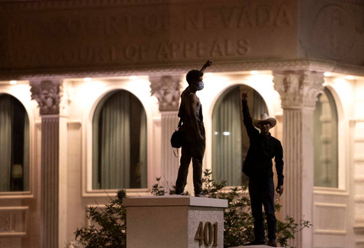 Protesters, demonstrating in honor of George Floyd and against police brutality, stand on struc ...