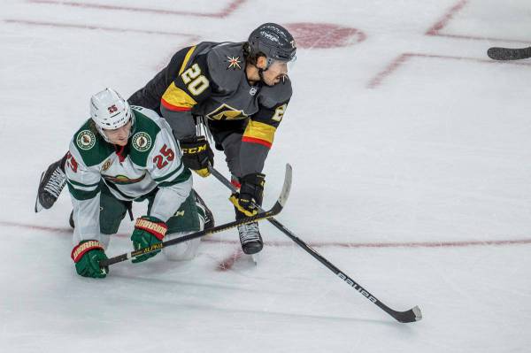 Golden Knights center Chandler Stephenson (20) eyes the puck as he tumbles over Minnesota Wild ...