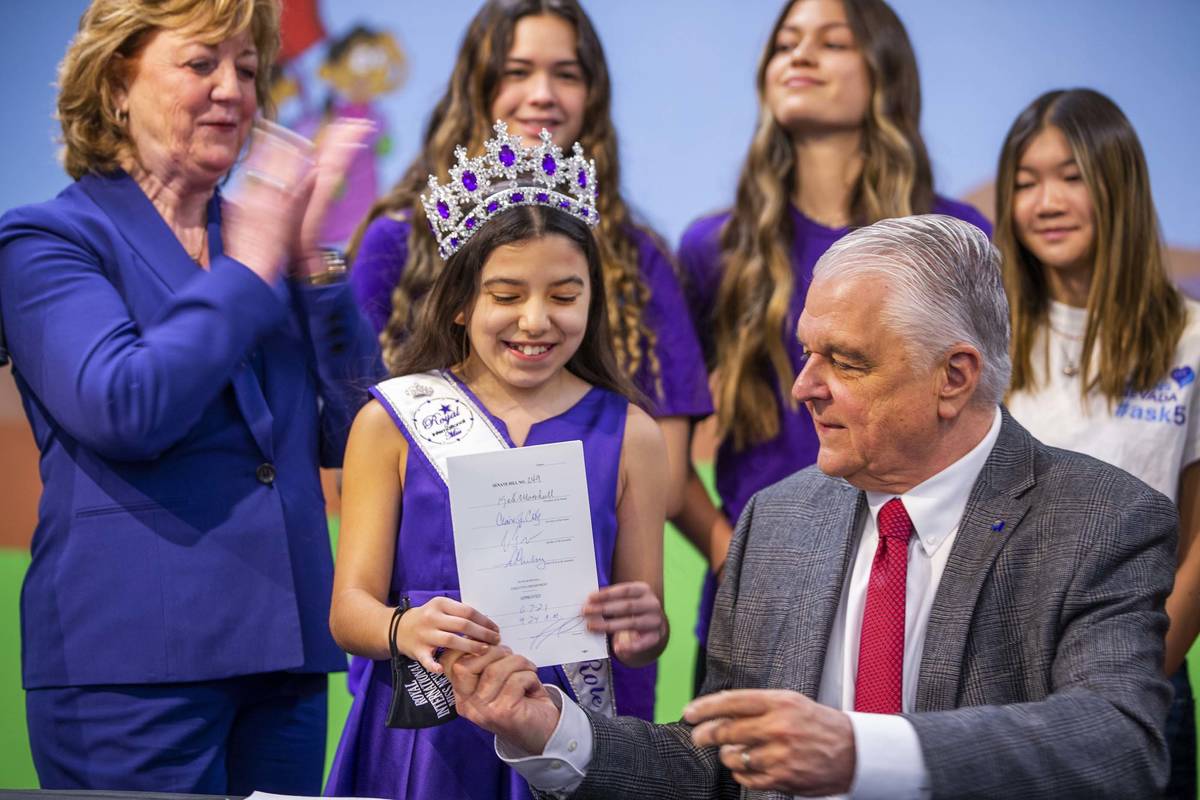 Gov. Steve Sisolak hands Miss Nevada Role Model Tayla Westerman his signed Senate Bill #249 dur ...