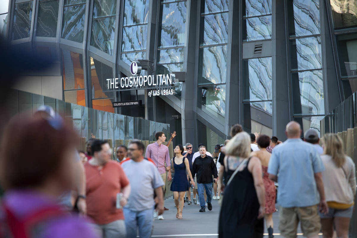 Visitors to the Las Vegas Strip cross a pedestrian bridge outside Cosmopolitan of Las Vegas on ...