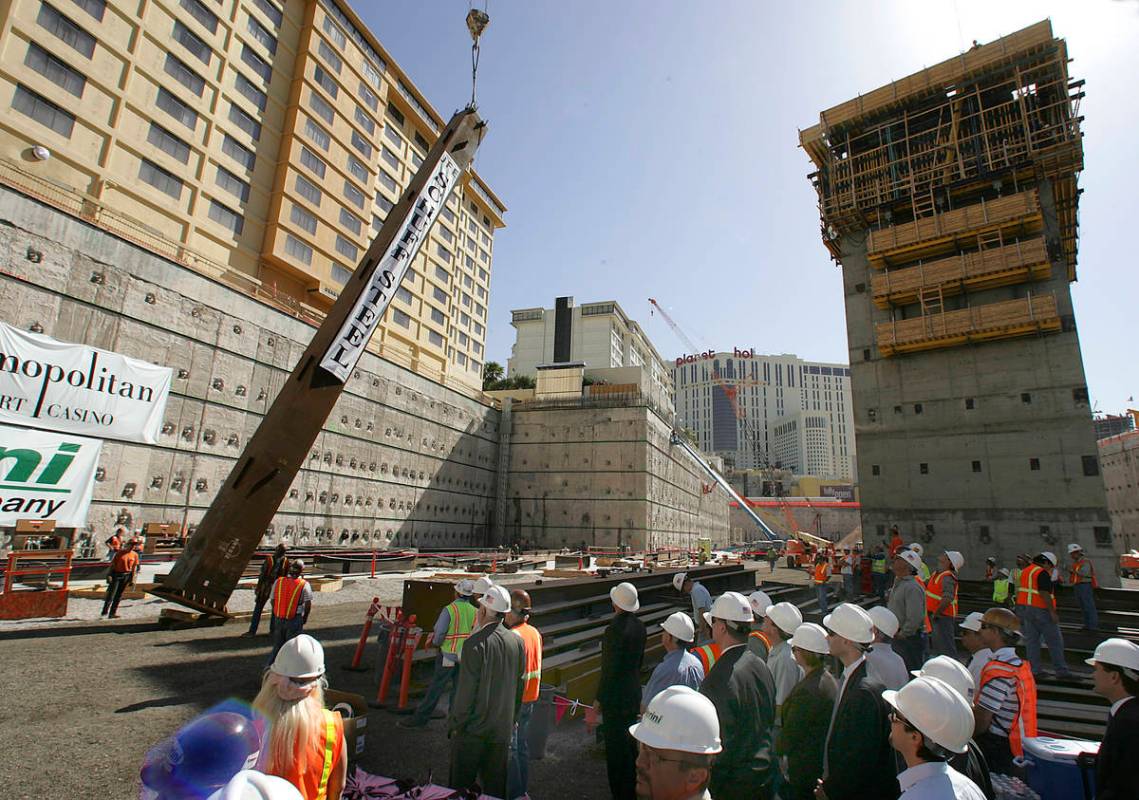 A steel column is hoisted into position as VIP guests and construction workers look on during a ...