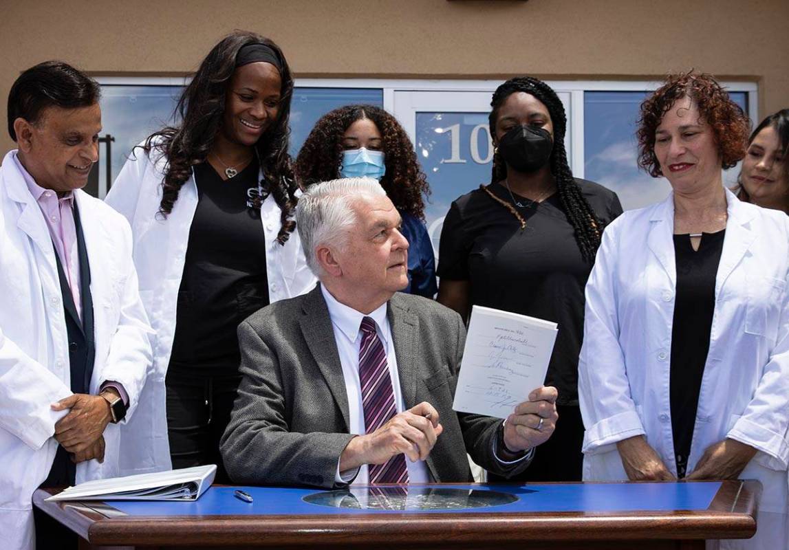 Gov. Steve Sisolak holds Senate Bill # 420, the bill that will provide a public health care opt ...