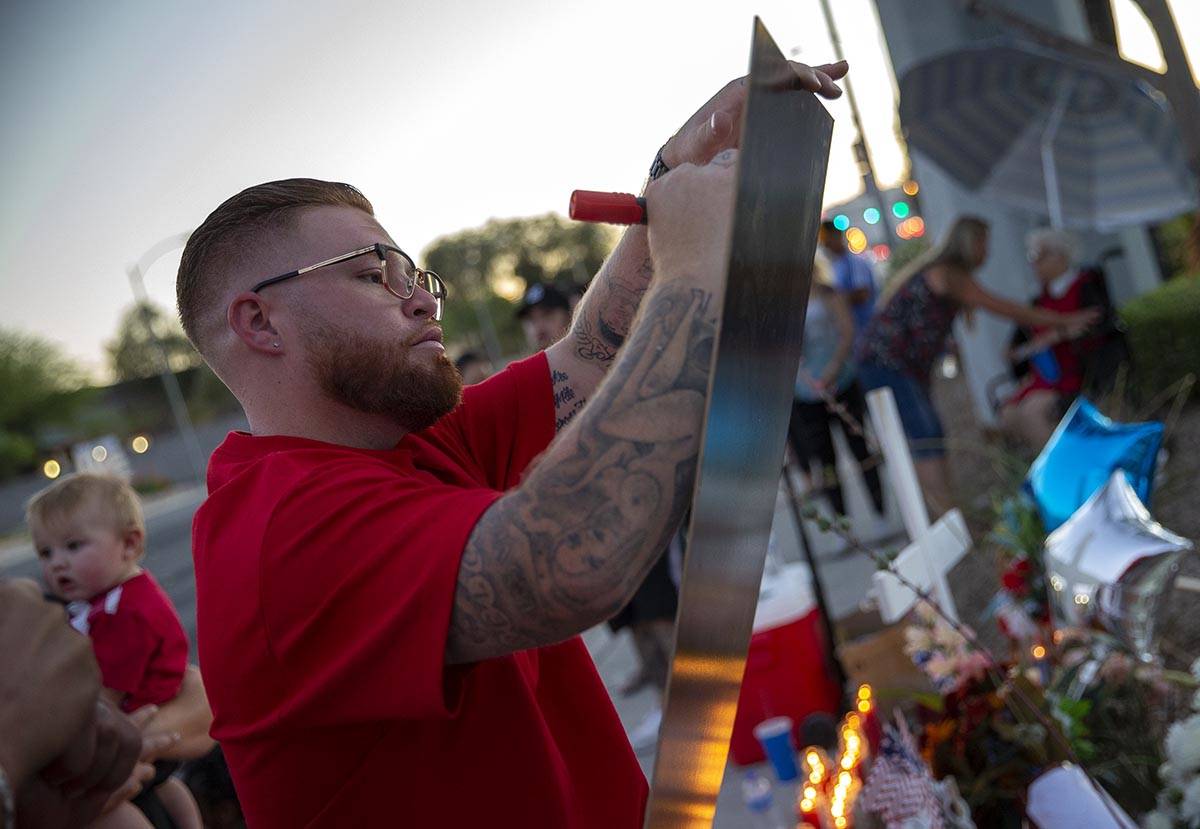 Ryan Anderson writes a message at a vigil for his father, Walter Anderson, near the intersectio ...