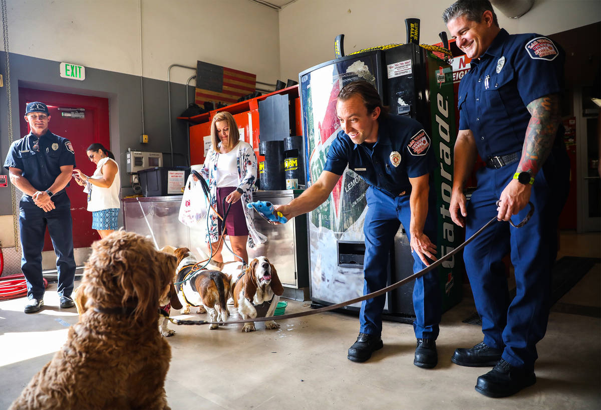 Tyler McFate, Station 1A operations chief, center, hands a toy to Murphy, a golden doodle, next ...