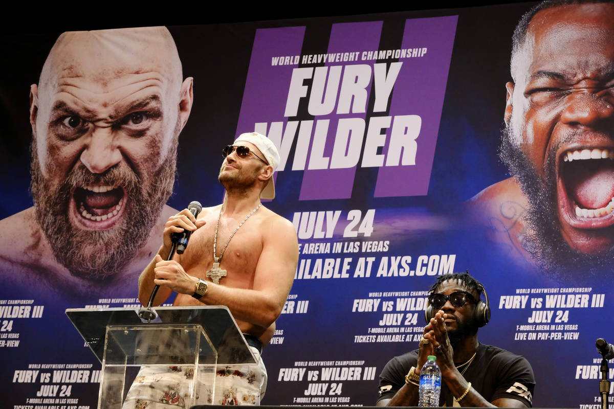 WBC Heavyweight Champion Tyson Fury, left talks during a news conference as Deontay Wilder look ...