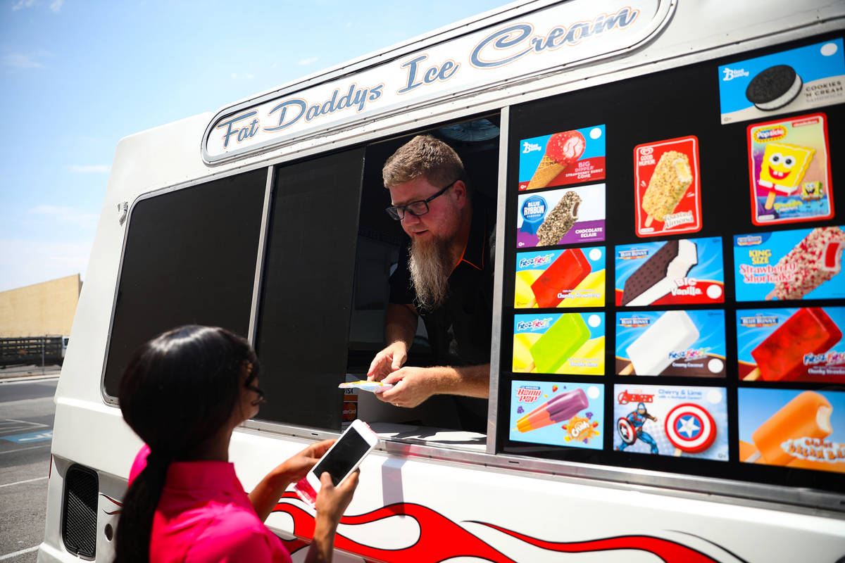 Al Davis, owner of Fat Daddys Ice Cream truck, hands ice cream to Jazmine Eady outside Caliber ...