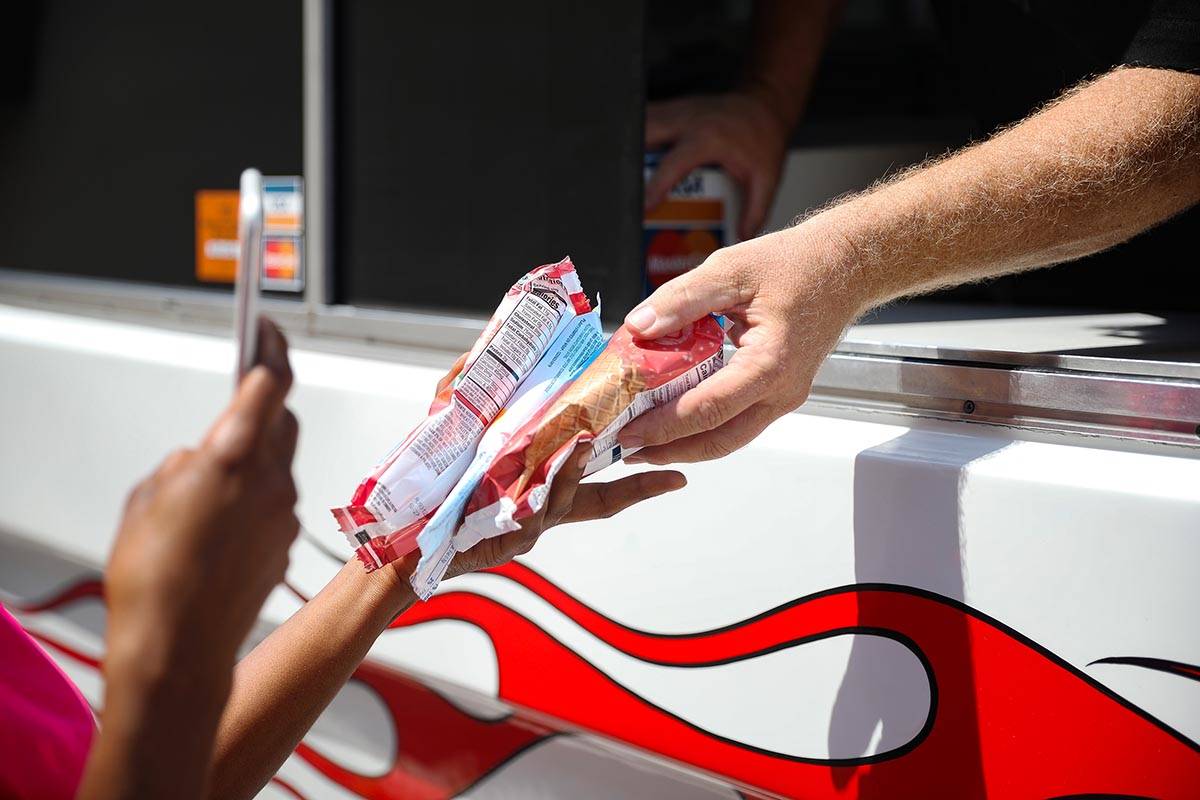 Al Davis, owner of Fat Daddy's Ice Cream truck, hands ice cream to Jazmine Eady outside Caliber ...