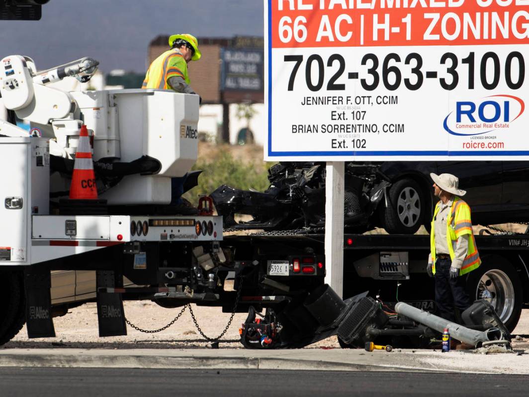 Workers remove a damaged traffic light after a multivehicle crash at the intersection of Warm S ...