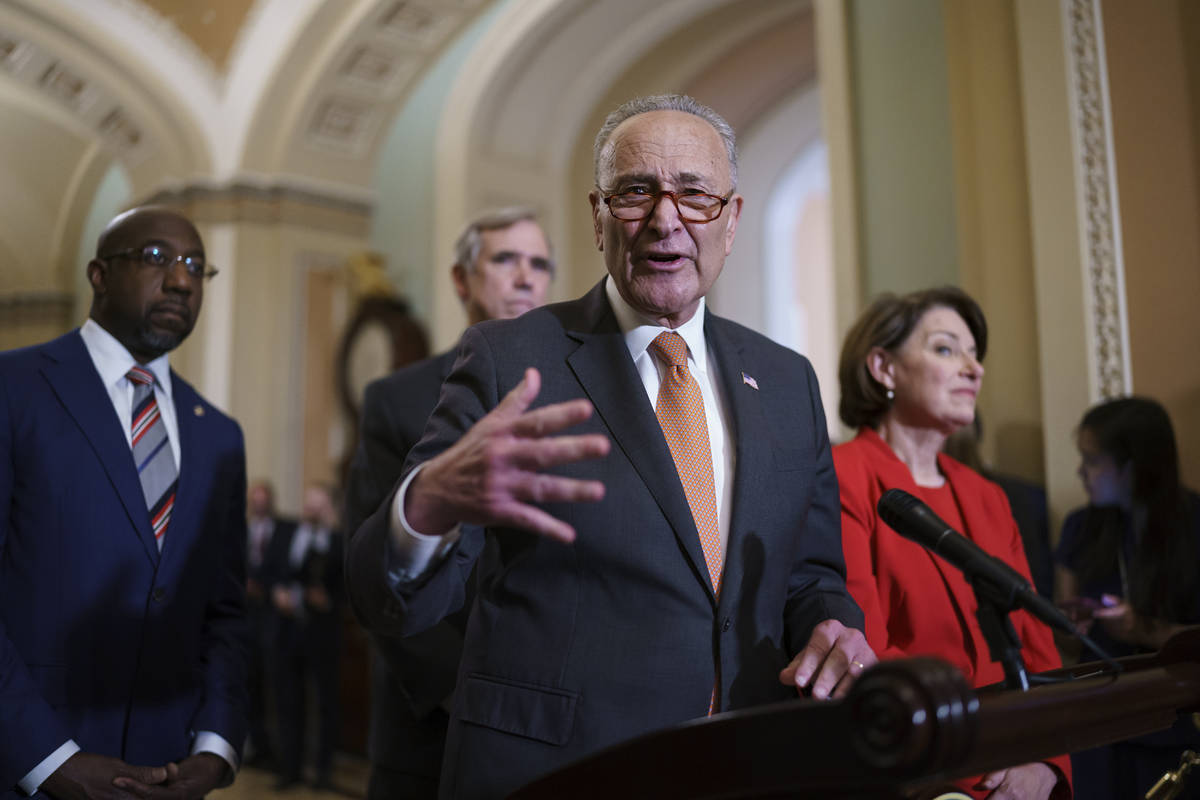 Senate Majority Leader Chuck Schumer, D-N.Y., flanked by Sen. Raphael Warnock, D-Ga., left, and ...