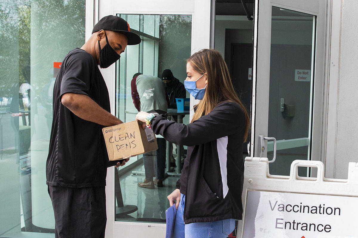 Ann Beck, right, a volunteer, hands out clean pens to a man who came to receive a COVID-19 vacc ...