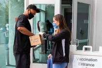 Ann Beck, right, a volunteer, hands out clean pens to a man who came to receive a COVID-19 vacc ...