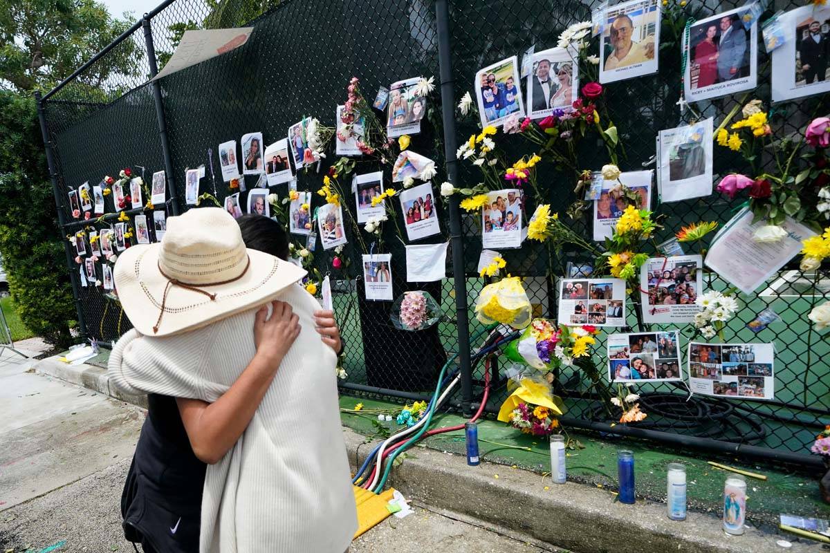 People embrace at a make-shift memorial outside St. Joseph Catholic Church, in Surfside, Fla., ...