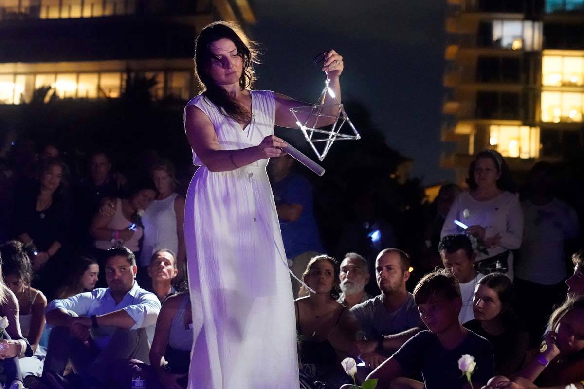 Michelle Cash plays a quartz crystal merkaba during a vigil, Monday, June 28, 2021, in Surfside ...