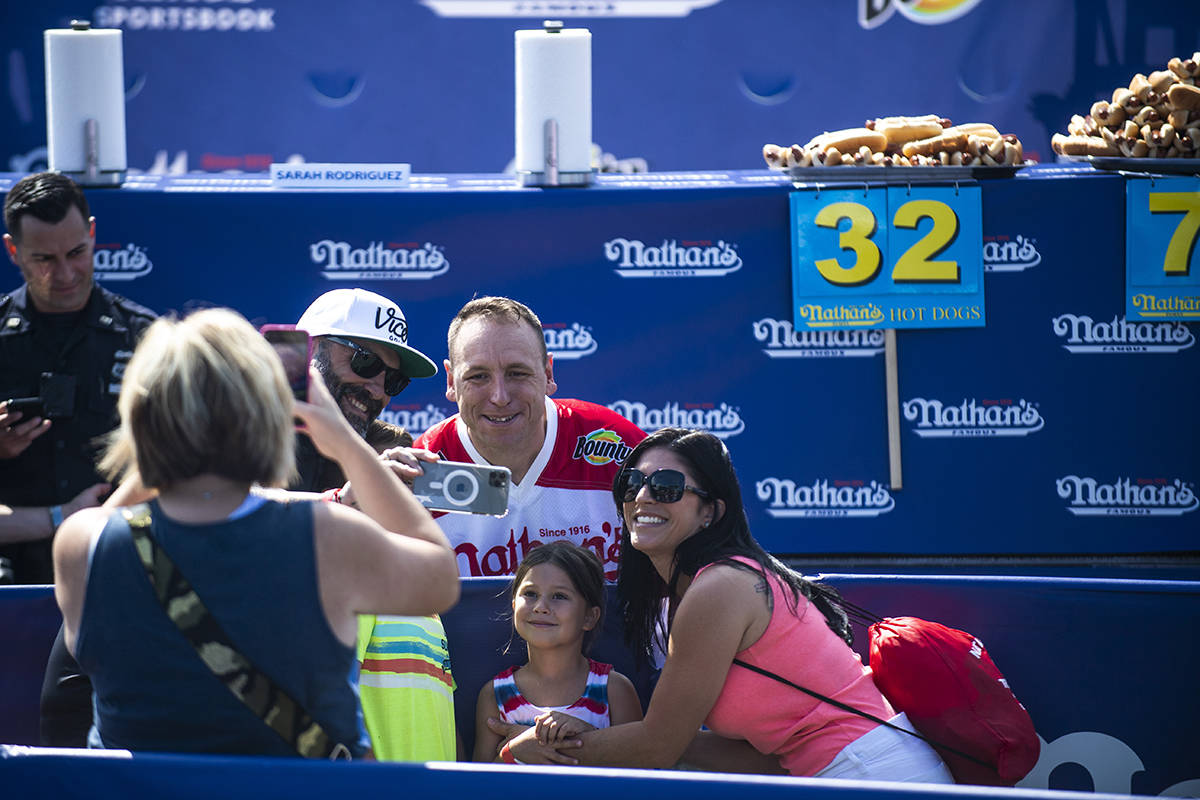 Winners Joey Chestnut and Michelle Lesco, obscured behind hot dogs, pose at the Nathan's Famous ...