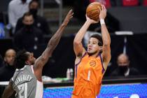 Phoenix Suns guard Devin Booker, right, shoots as Los Angeles Clippers guard Patrick Beverley d ...