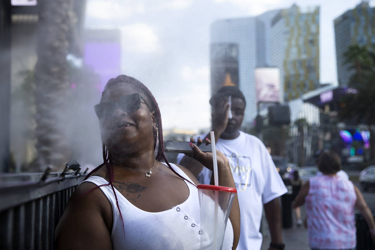 Rhea Barrett, of Chicago, cools off in the mist outside Hexx Kitchen and Bar on Wednesday, July ...