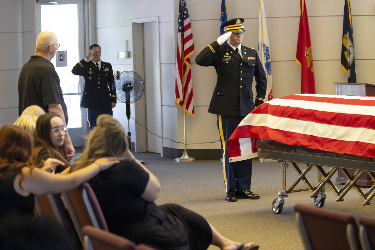 U.S. Army Lt. Kris Hayman salutes the flag-draped casket during a funeral service for retired N ...