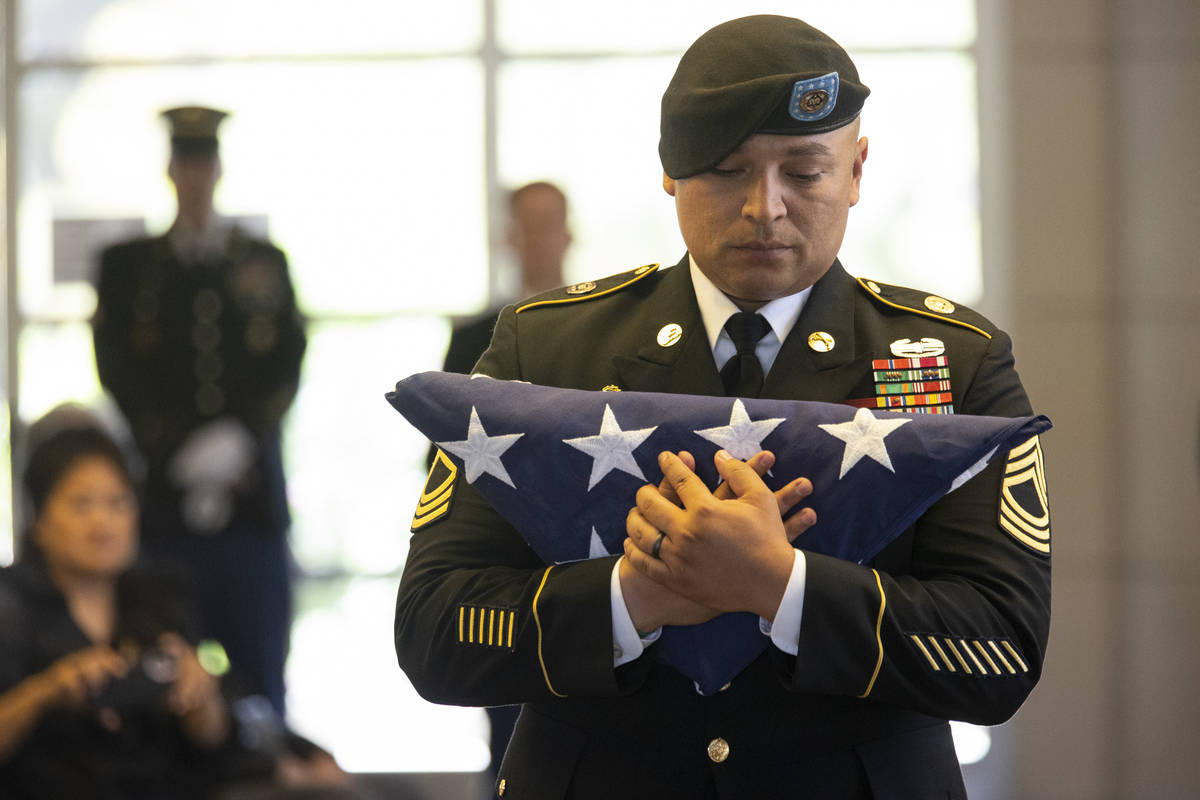 U.S. Army Master Sgt. Rafael Aguilera holds the American flag before presenting it to the famil ...