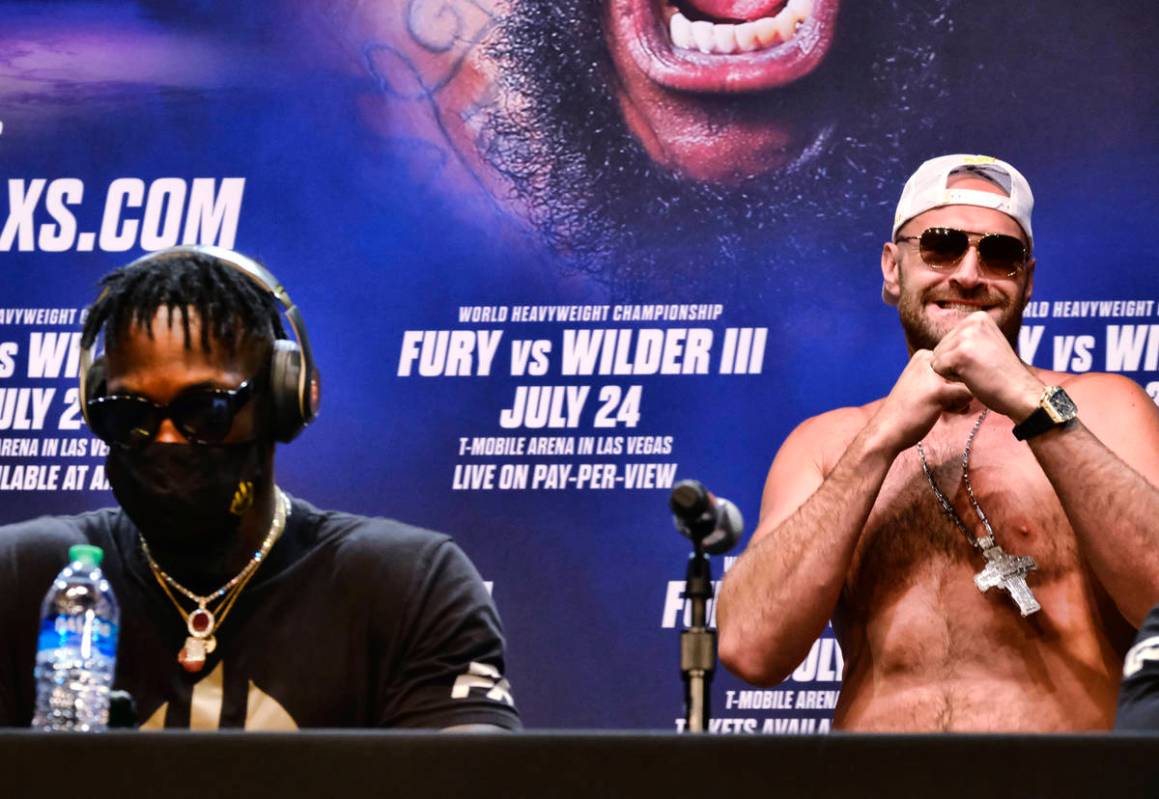 WBC heavyweight champion Tyson Fury, right, raises his fists as he walks near Deontay Wilder at ...