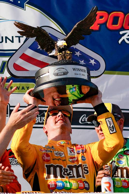Kyle Busch raises the trophy after winning a NASCAR Cup Series auto race at Pocono Raceway, Sun ...