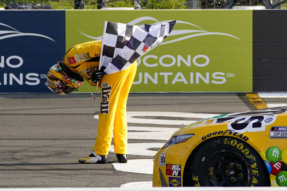 Kyle Busch takes a bow with the checker flag after winning a NASCAR Cup Series auto race at Poc ...