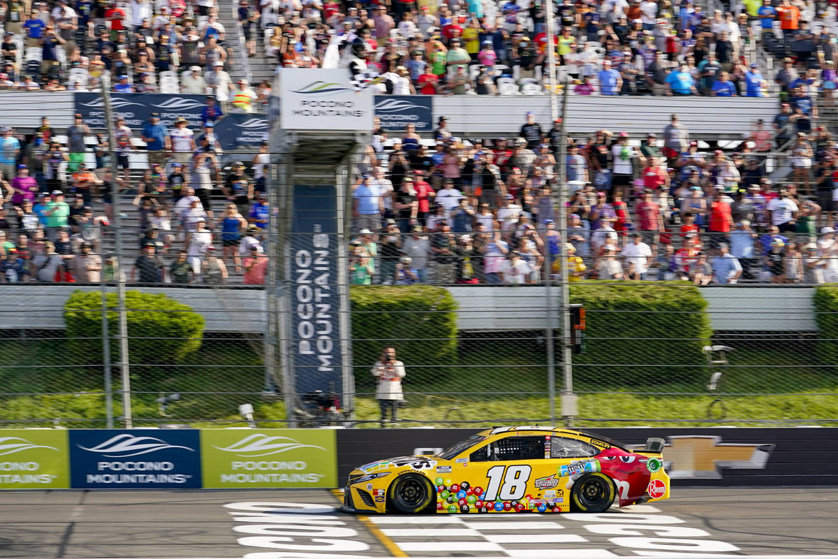 Kyle Busch (18) takes the checker flag to win the NASCAR Cup Series auto race at Pocono Raceway ...