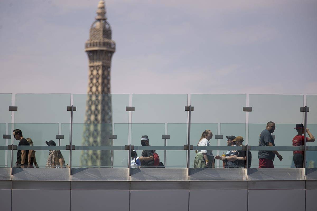 People walk the pedestrian bridge near the Park MGM hotel-casino in Las Vegas, Saturday, July 1 ...