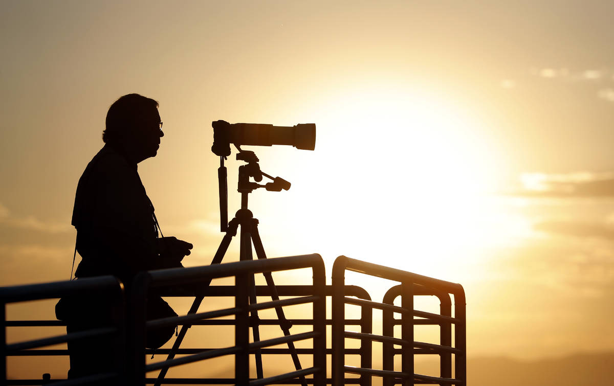 A photographer prepares his camera as the sun rises over Spaceport America before Virgin Galact ...