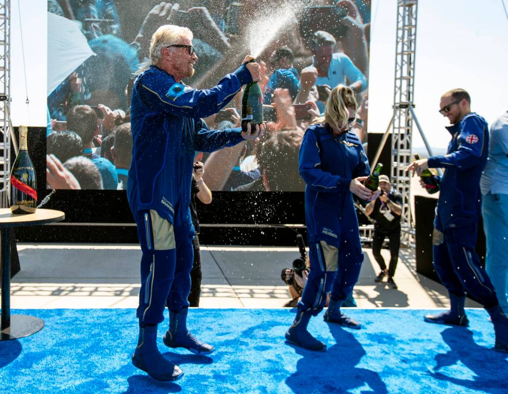 Virgin Galactic founder Richard Branson, left, sprays champagne to crew members Beth Moses and ...