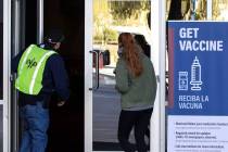 A FEMA volunteer leads a woman into the Las Vegas Convention Center's vaccine distribution area ...