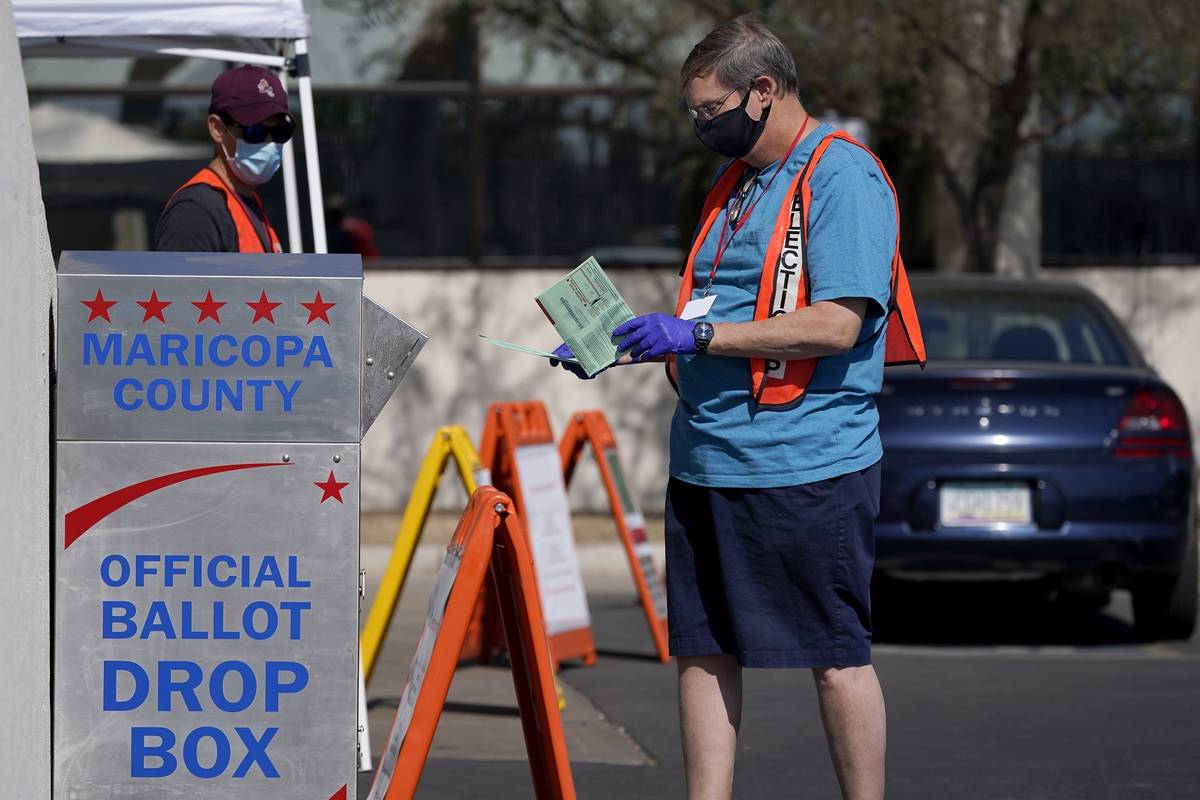 FILE - In this Tuesday, Oct. 20, 2020 file photo, volunteers help voters as voters drop off the ...