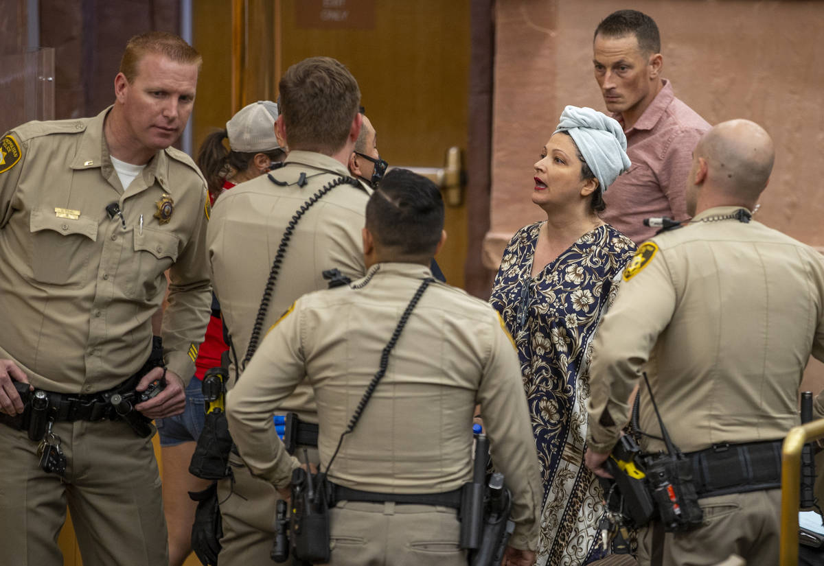 Officers speak with Katrin Ivanoff during the Clark County Commission meeting for public outbur ...