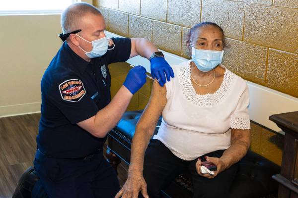 Chris Racine of Las Vegas Fire Rescue administers a COVID-19 vaccine to the Stella Fleming Towe ...