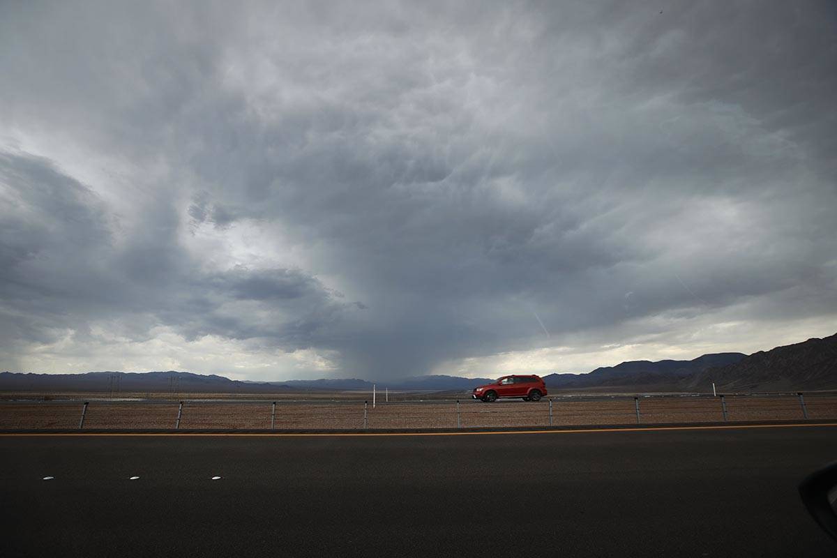 A car drives on U.S. Route 93 near Boulder City, Wednesday, July 21, 2021, as dark clouds drift ...