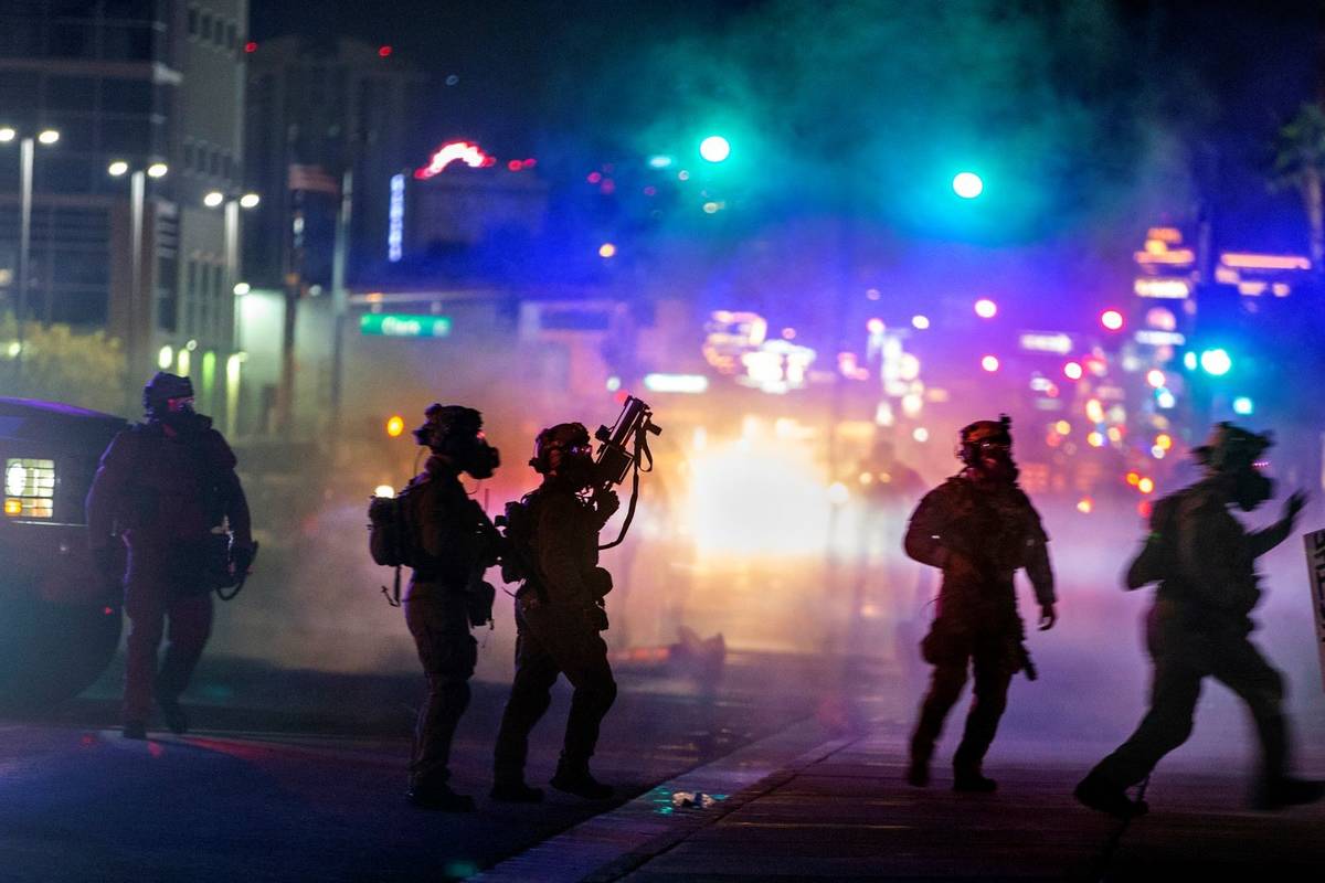 Las Vegas police are engulfed in tear gas during a protest along Las Vegas Boulevard on May 30, ...